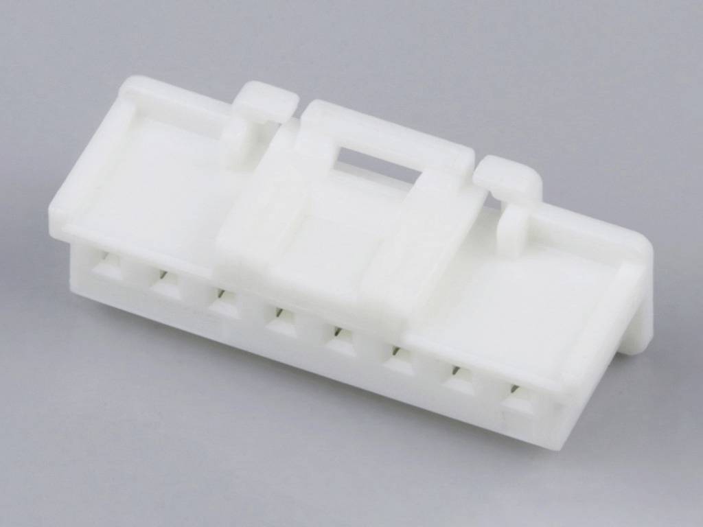White plastic connector with a square shape and multiple connection points, lying on a grey surface.