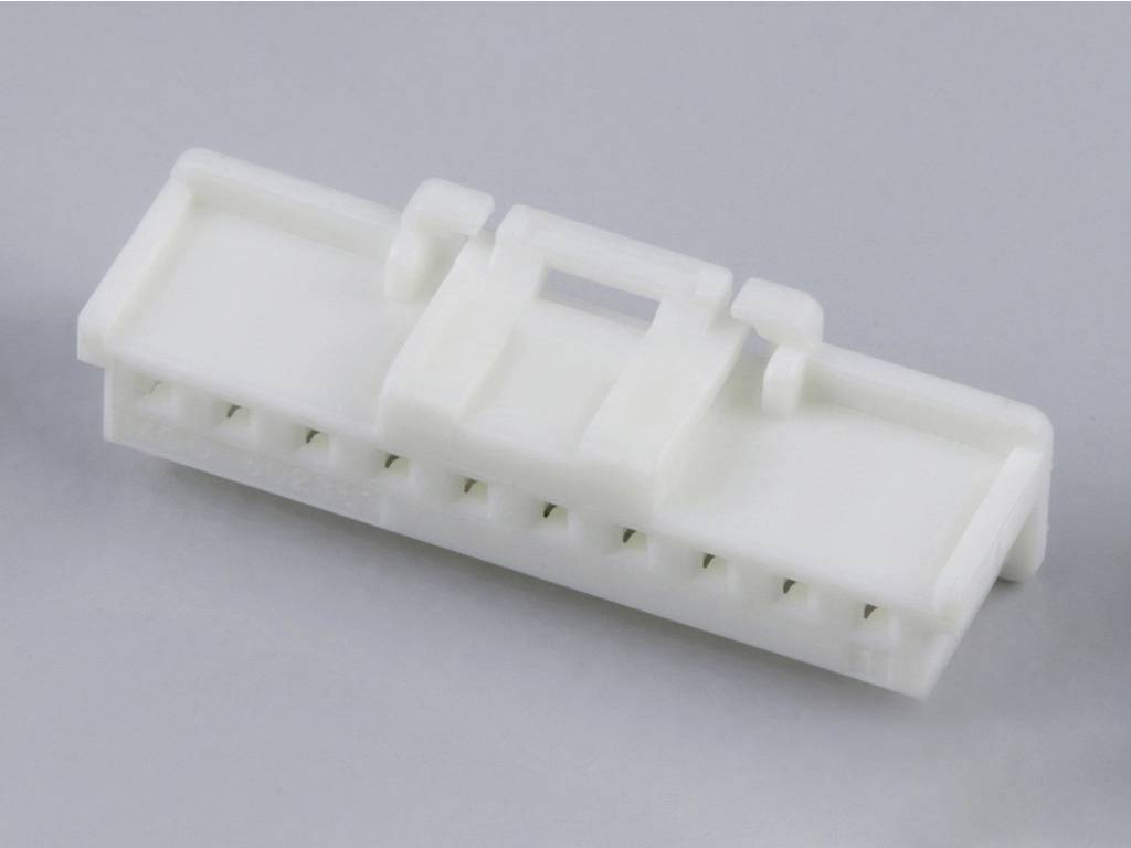 A white plastic connector with multiple connection openings on a grey surface, used in electronic devices.
