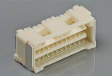 A white electrical connector with multiple pins is lying on a grey surface.