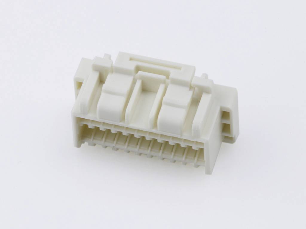 A white plastic plug with multiple sockets and a rectangular housing, placed on a light surface.