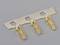 Three golden electrical connectors on a metallic carrier, against a grey background.