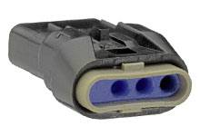 A black electrical connector with three blue terminals, lying flat on a surface, close-up.