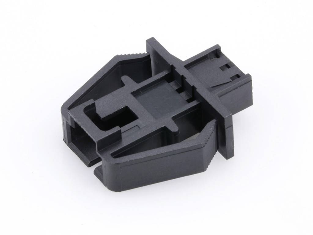 A black plastic component with a rectangular base and asymmetrically positioned prongs. It appears to be a connector or mounting bracket.