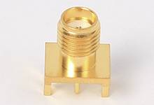 Golden, cylindrical connector on a rectangular base, suitable for electronic applications, standing on four legs.