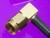 A golden, right-angled plug on a black cable against a purple background.