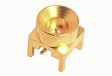 Small, square, gold-coloured component with a circular recess on top, presumably an electrical connector element.
