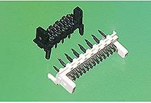 Two rows of electrical plug pins, one black and one white, placed side by side on a green background.
