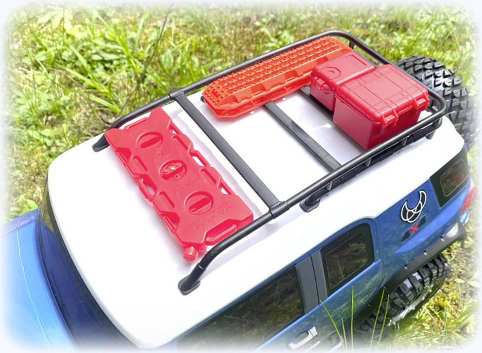 Toy car parked in blue and white on the grass. Red tools and containers are located on the roof rack.