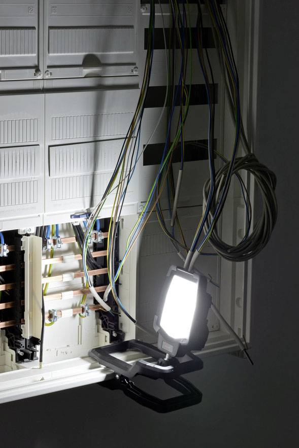 An open fuse box with cables, illuminated by a lamp.