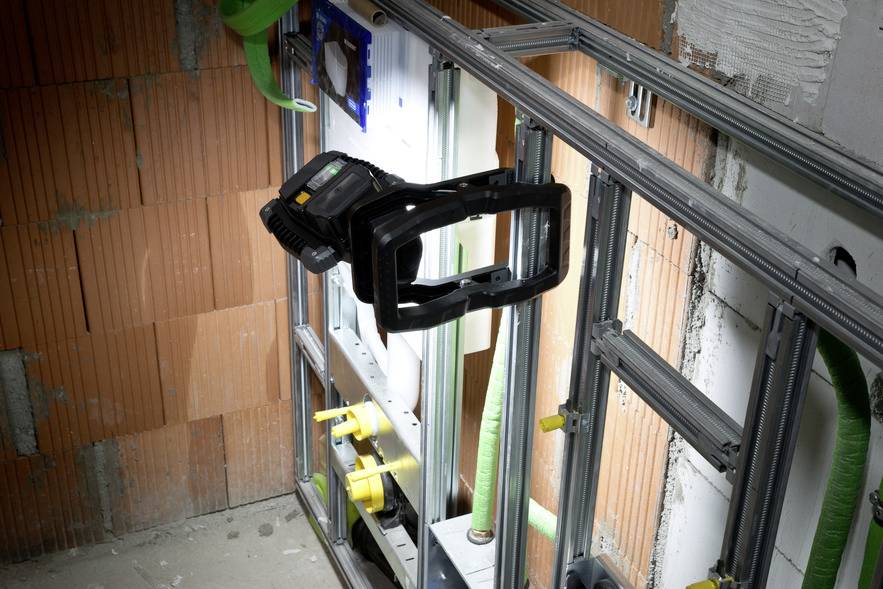 A construction site with exposed brick walls and metal frames, where a work light emphasises an illuminated area.