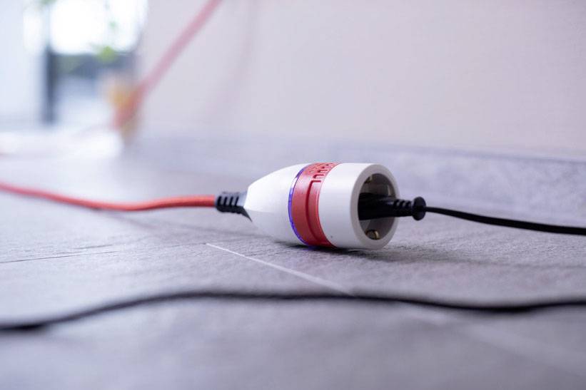 A socket connection lying on the ground: A red cable is connected to a white and red adapter.