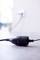 A black network cable with a plug is lying on the floor, with a blurry socket on the wall visible in the background.