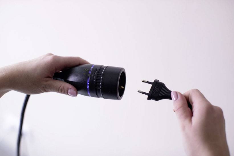 Two hands are holding a plug and a socket, about to be connected. The background is out of focus.