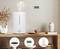 Humidifier on a table, emitting steam. A digital clock hanging on the wall. Decorative vases in the background.