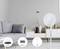 Modern living room decoration with a grey sofa, digital clock on the wall and a fan. Symbols below show router, sensor, fan.