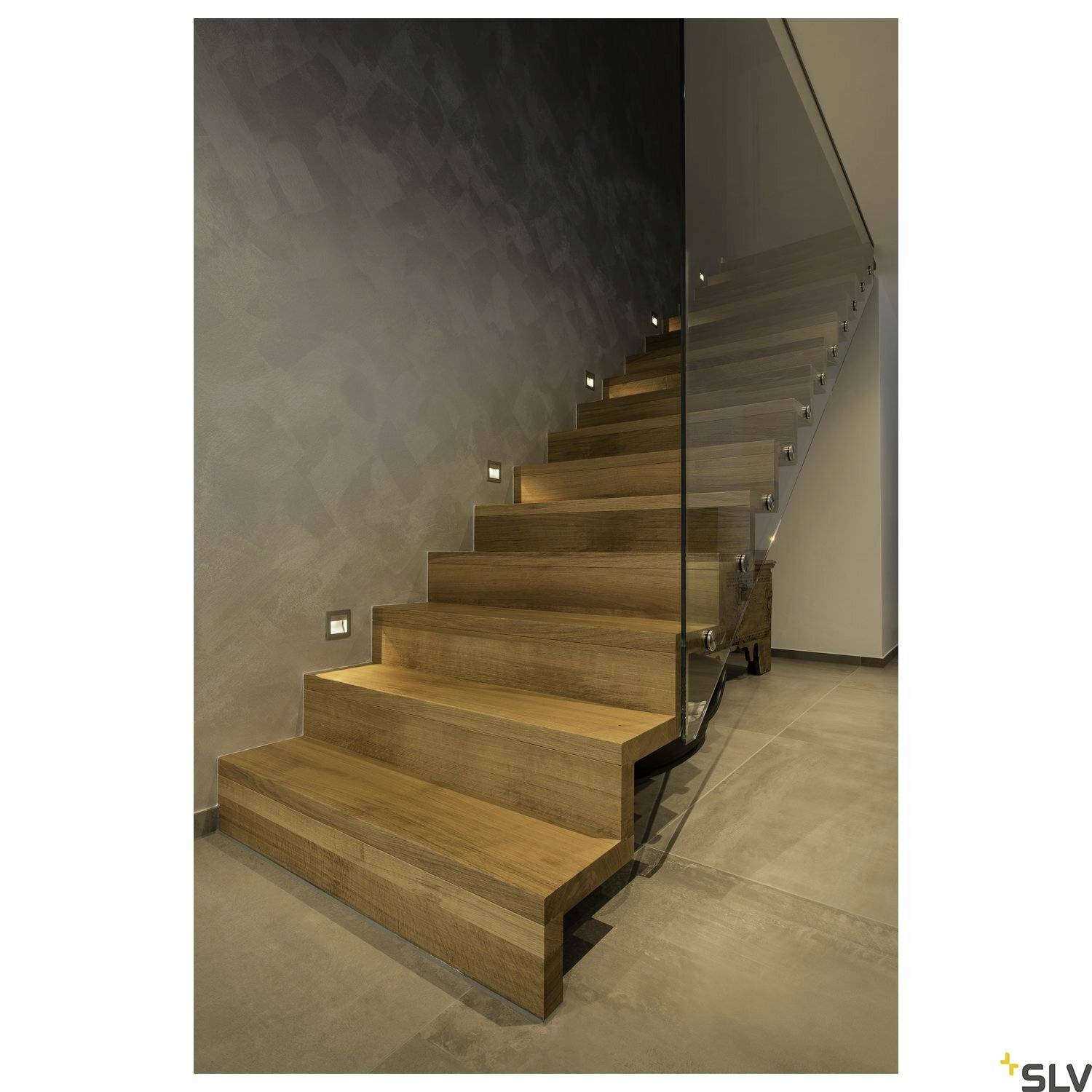 Modern wooden staircase with integrated LED lighting against a grey wall, ascending upwards.
