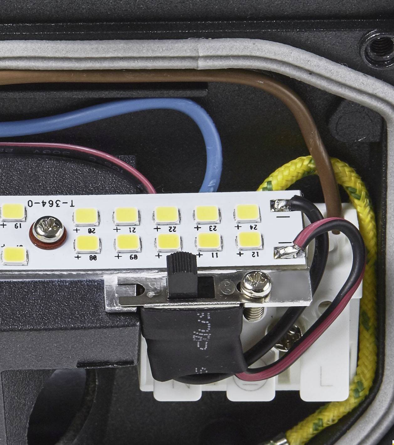 LED strip in electrical circuit with colour-coded wires; Blue and Black on the left, Red on the right. Yellow cable protection on top.