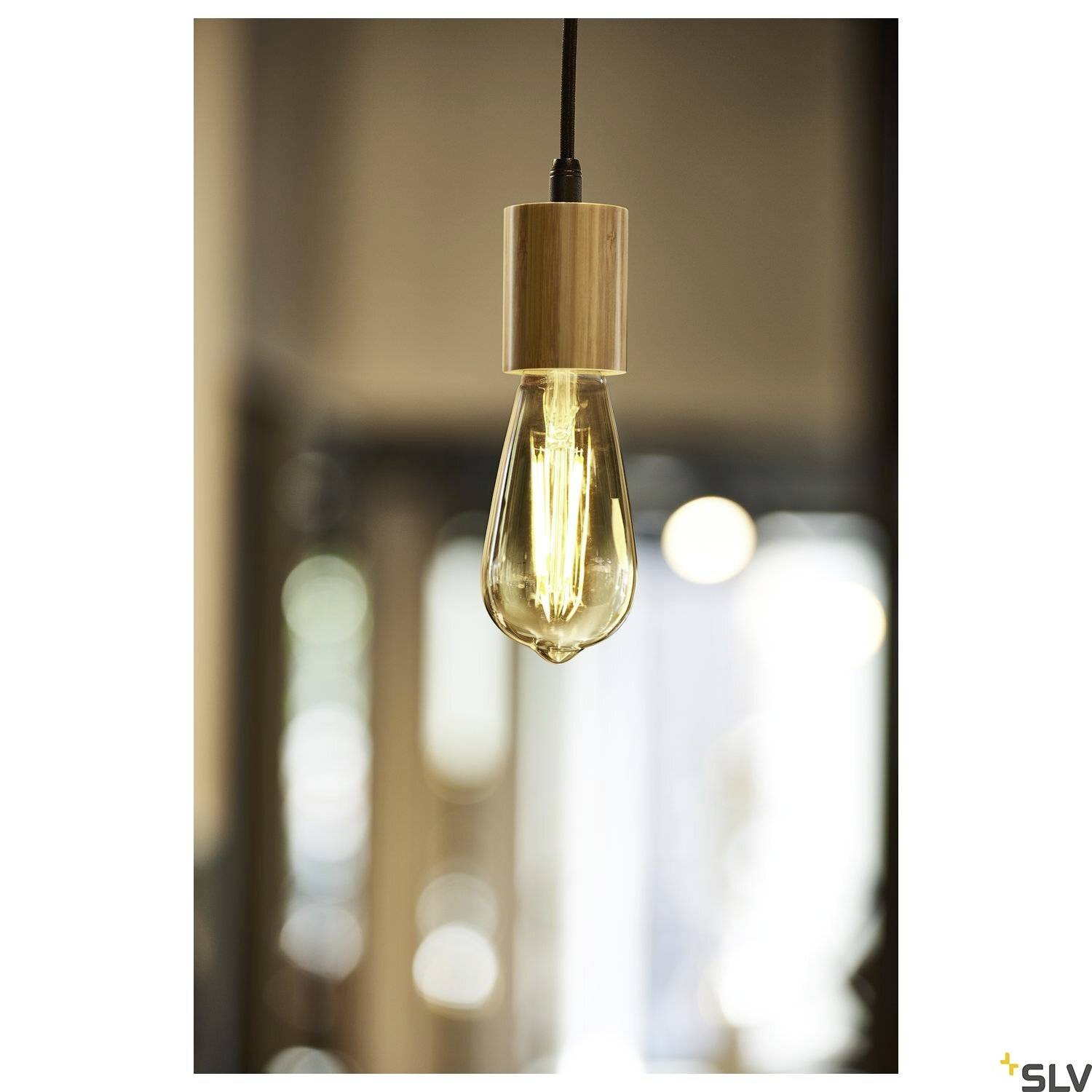 A hanging light bulb with warm light in a blurred interior. The fitting is made of wood.