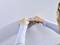 A person is attaching a small, white plastic component to a textured white wall. Hands and the part are in focus.
