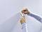 A person carefully removes a self-adhesive hook strip from a textured white wall.