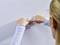 A person attaches a hook to a white textured wall with their hands.