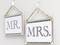 Two signs on the wall with the inscriptions 'Mr.' and 'Mrs.', hung on transparent hooks using ropes.