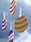 Colourful, striped and zigzag-patterned Christmas baubles hang against a blue sky.