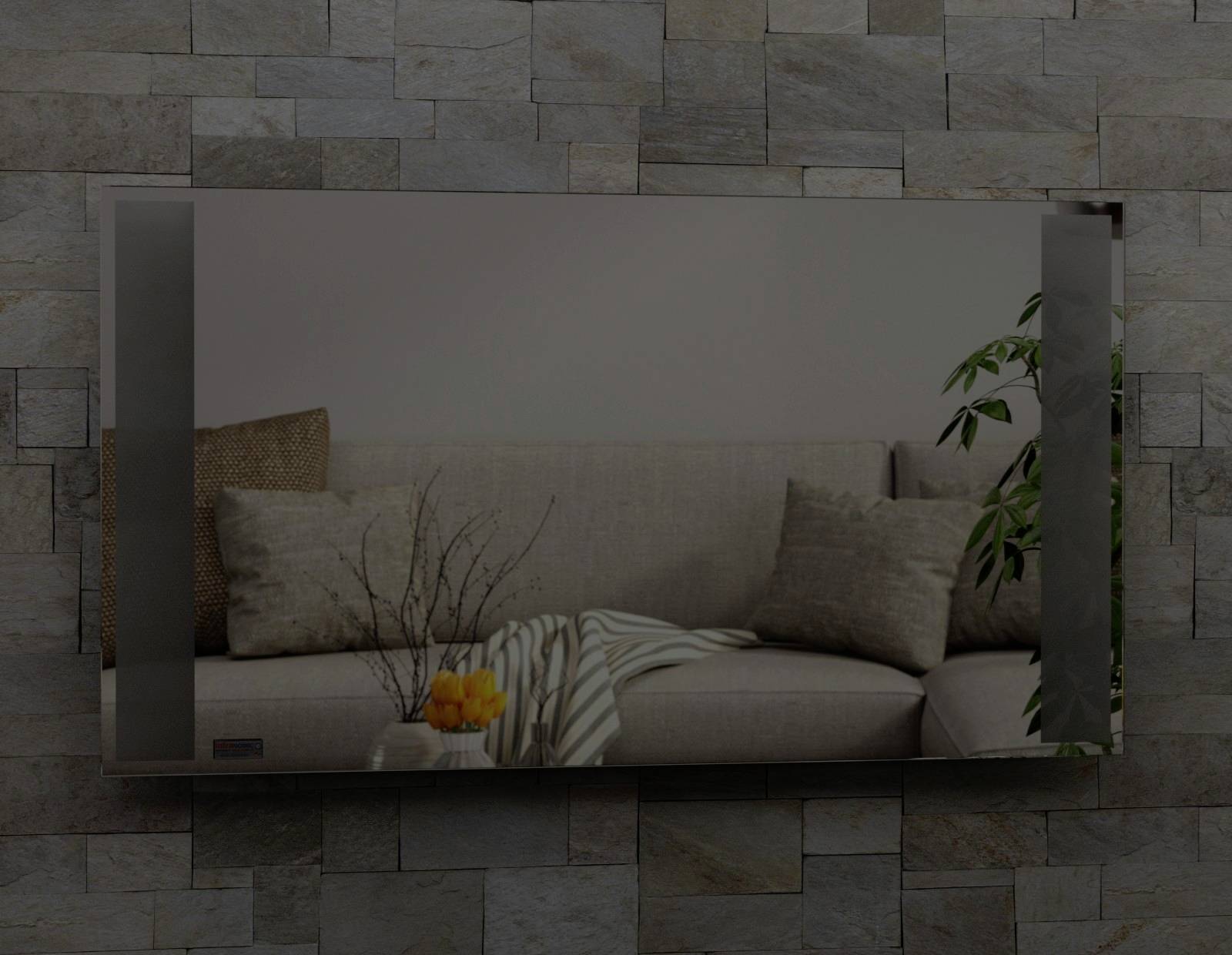 Living room with a grey sofa, cushions and throw. Decoration: vase with branches, yellow and green plants. Stone tile wall.