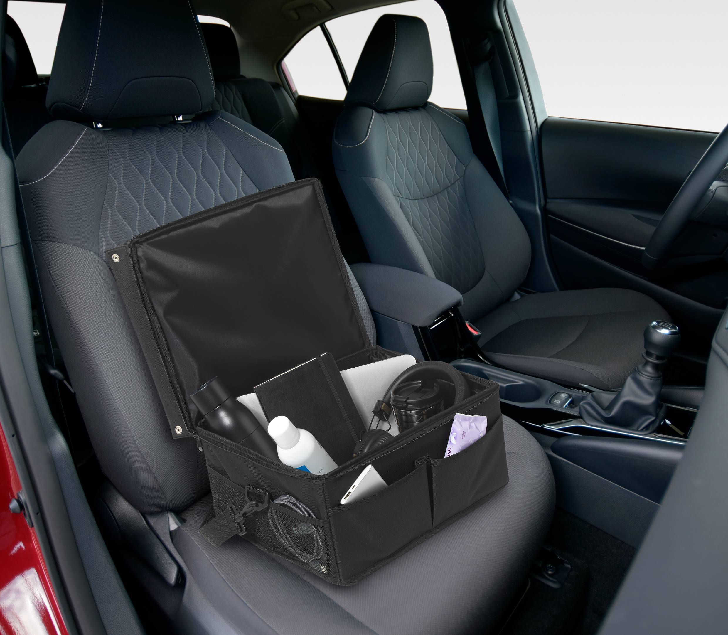 Open black box with car care products on the passenger seat of a car, next to a black centre console and grey seats.