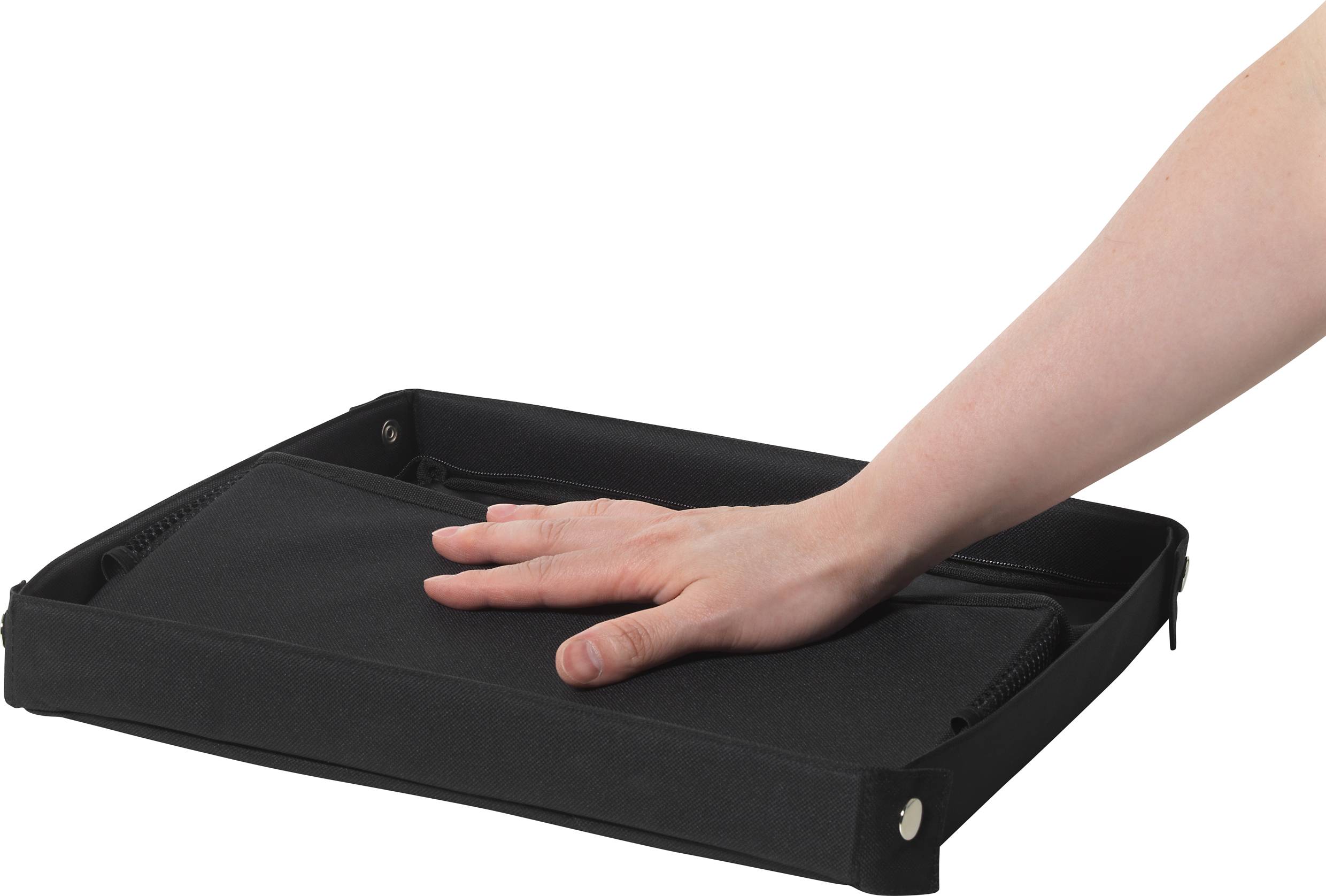 A hand is pressing down on a flat, black, foldable box.