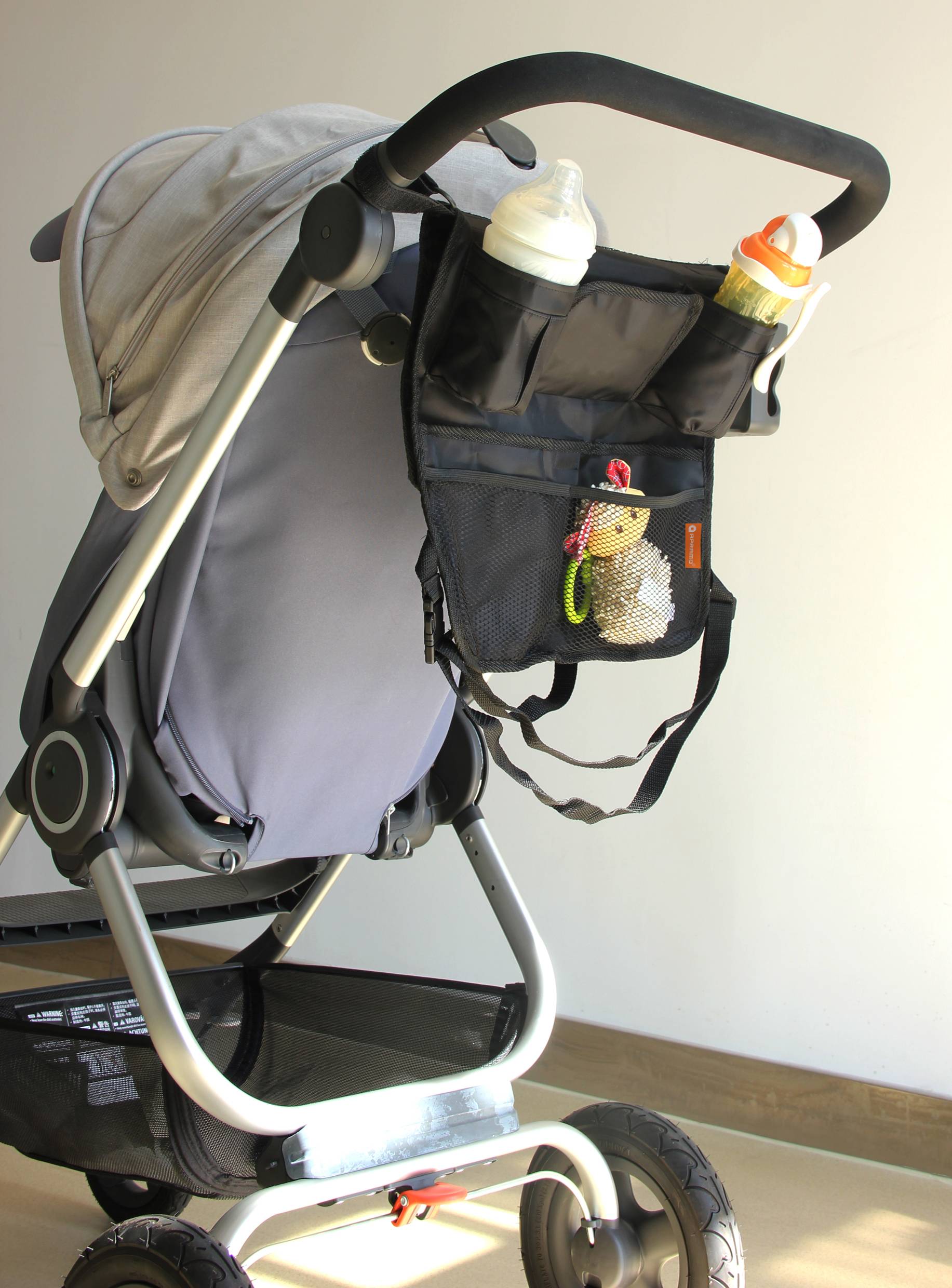 Pushchair with an attached bottle bag, containing two baby bottles and a small toy.