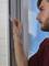 A person is attaching a window mesh to a window frame to keep insects outside.