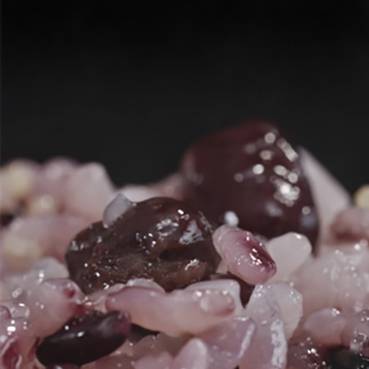 Close-up of reddish, coarse-grained sea salt mixed with dark peppercorns.