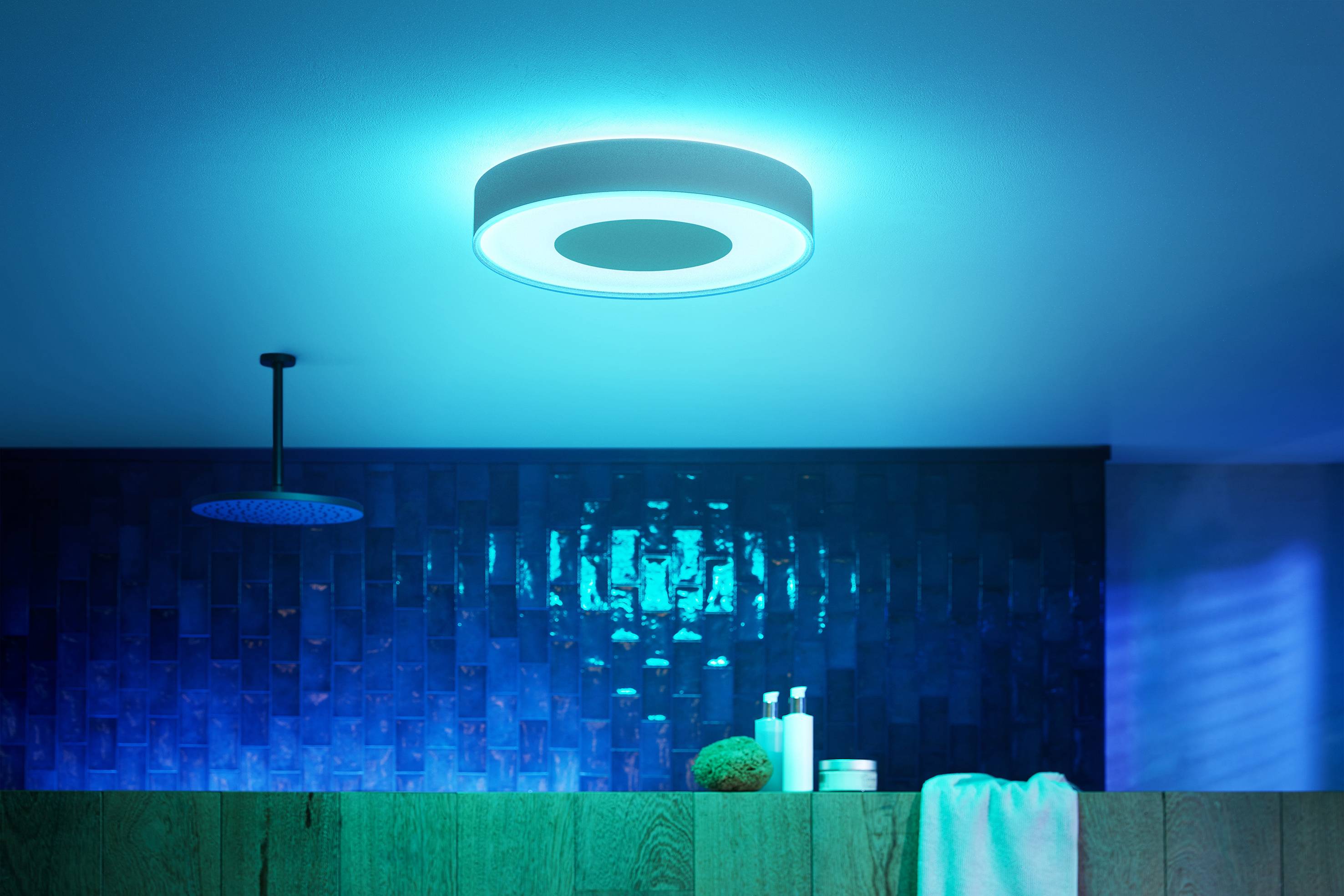 A bathroom with blue tiles and soft lighting from a circular ceiling light, creating a soothing ambience.