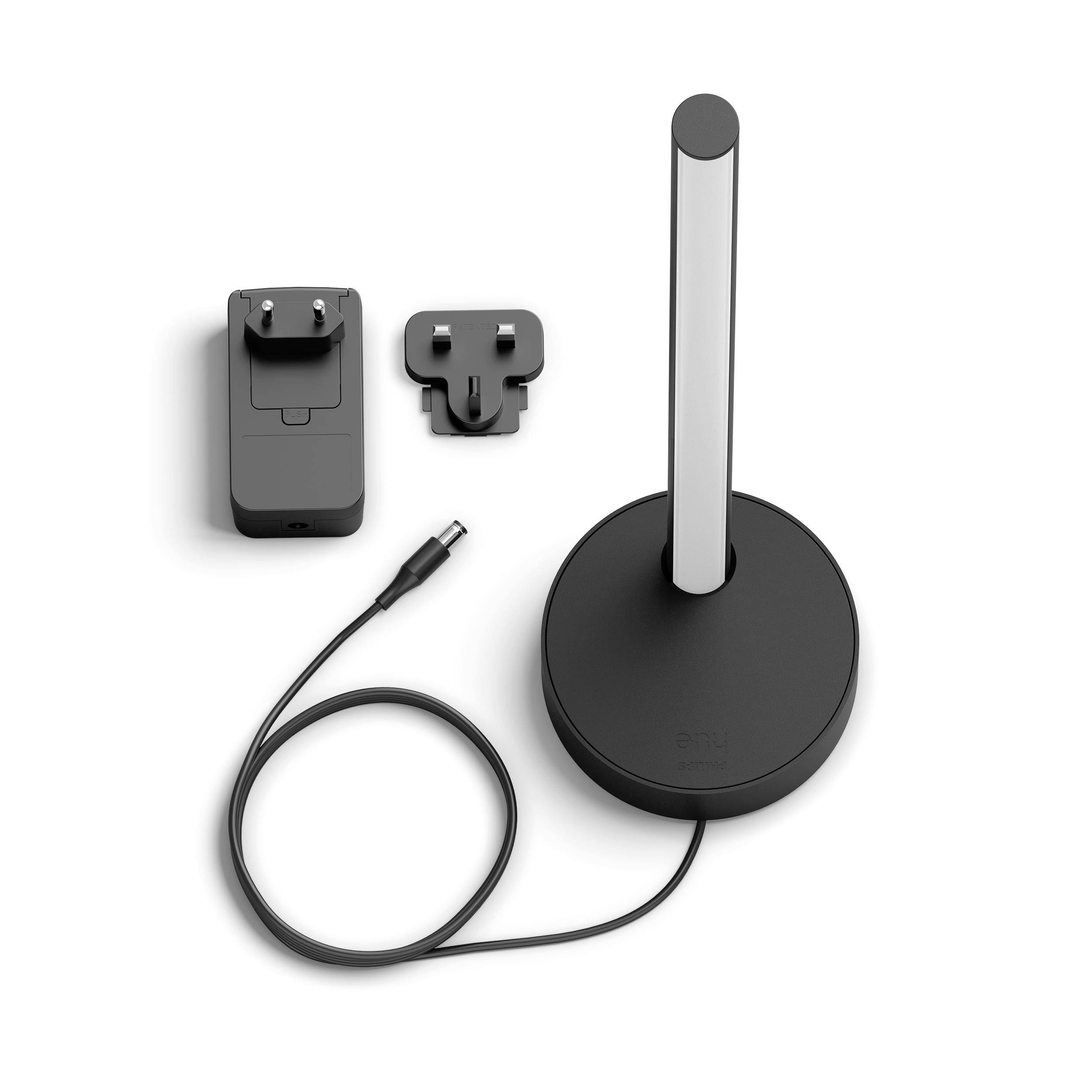 A black wireless charging base with a silver stand, next to a charger with two interchangeable plugs.