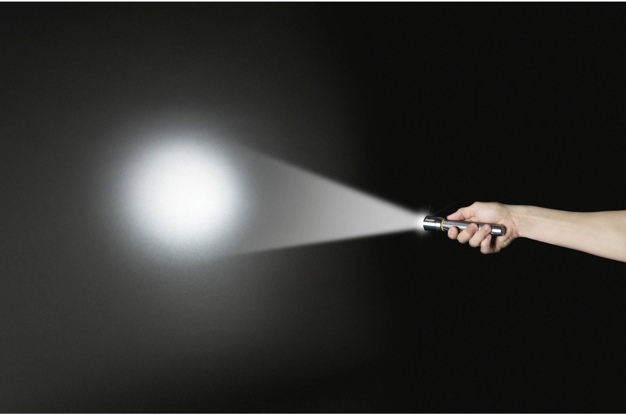 A hand holds a torch, its beam of light directed into the darkness.