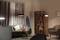 Cosy living room with a grey sofa, cushions, side table with fruit, surfboard on the wall, standard lamp and bookshelf.