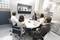 Six people in a conference room are conducting a video meeting. Four people are visible online on the screen.