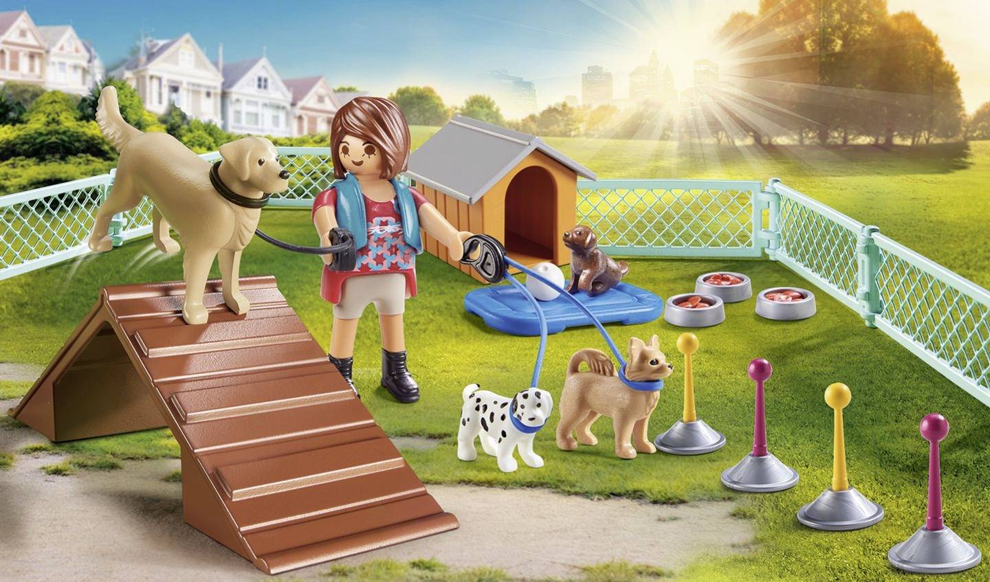 A game character trains dogs in a fenced play area outdoors with a kennel, obstacles, and food bowls.