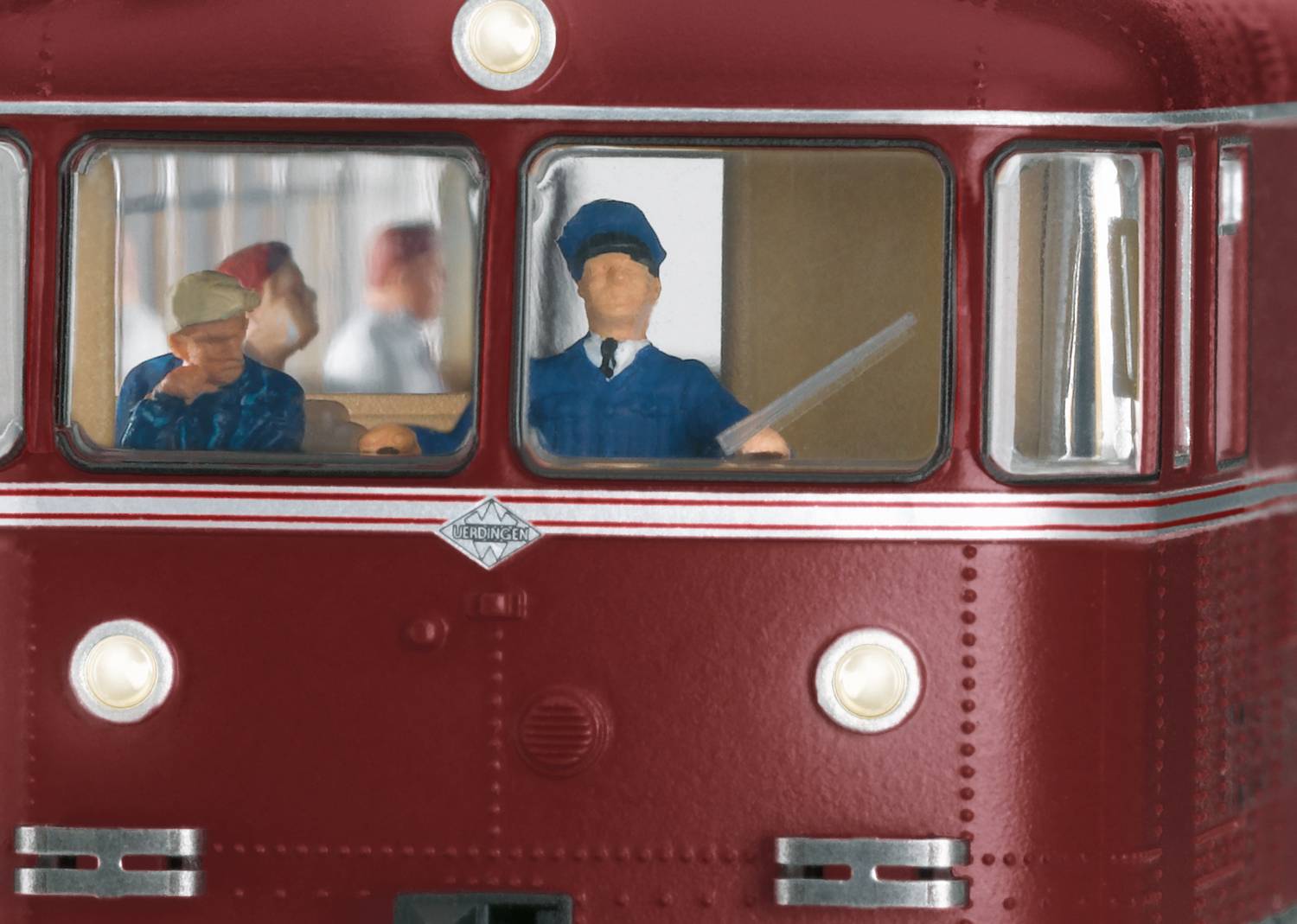 A red model of a historical locomotive with three figures seated in the cab, wearing different uniforms.