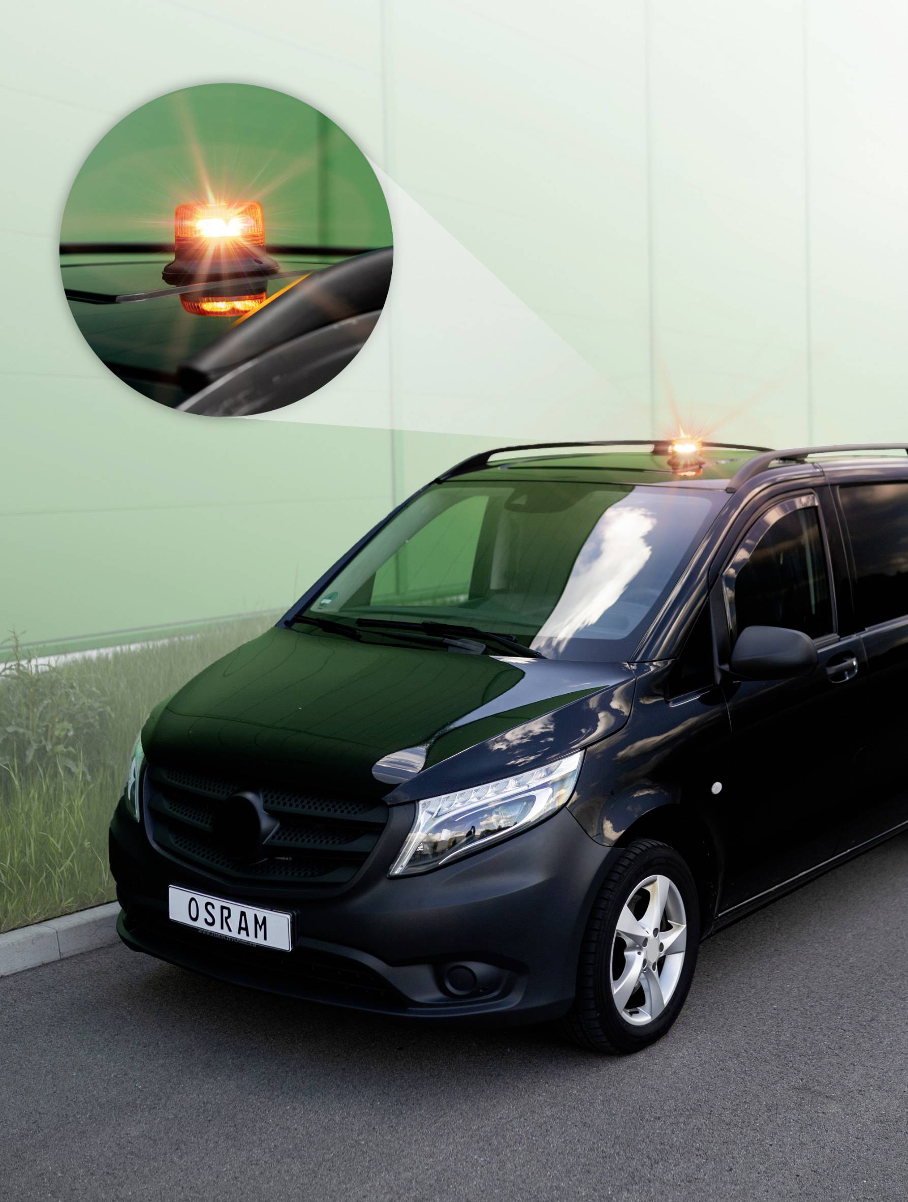 Black delivery van with illuminated orange warning light on the roof. Enlarged section shows the active warning light.