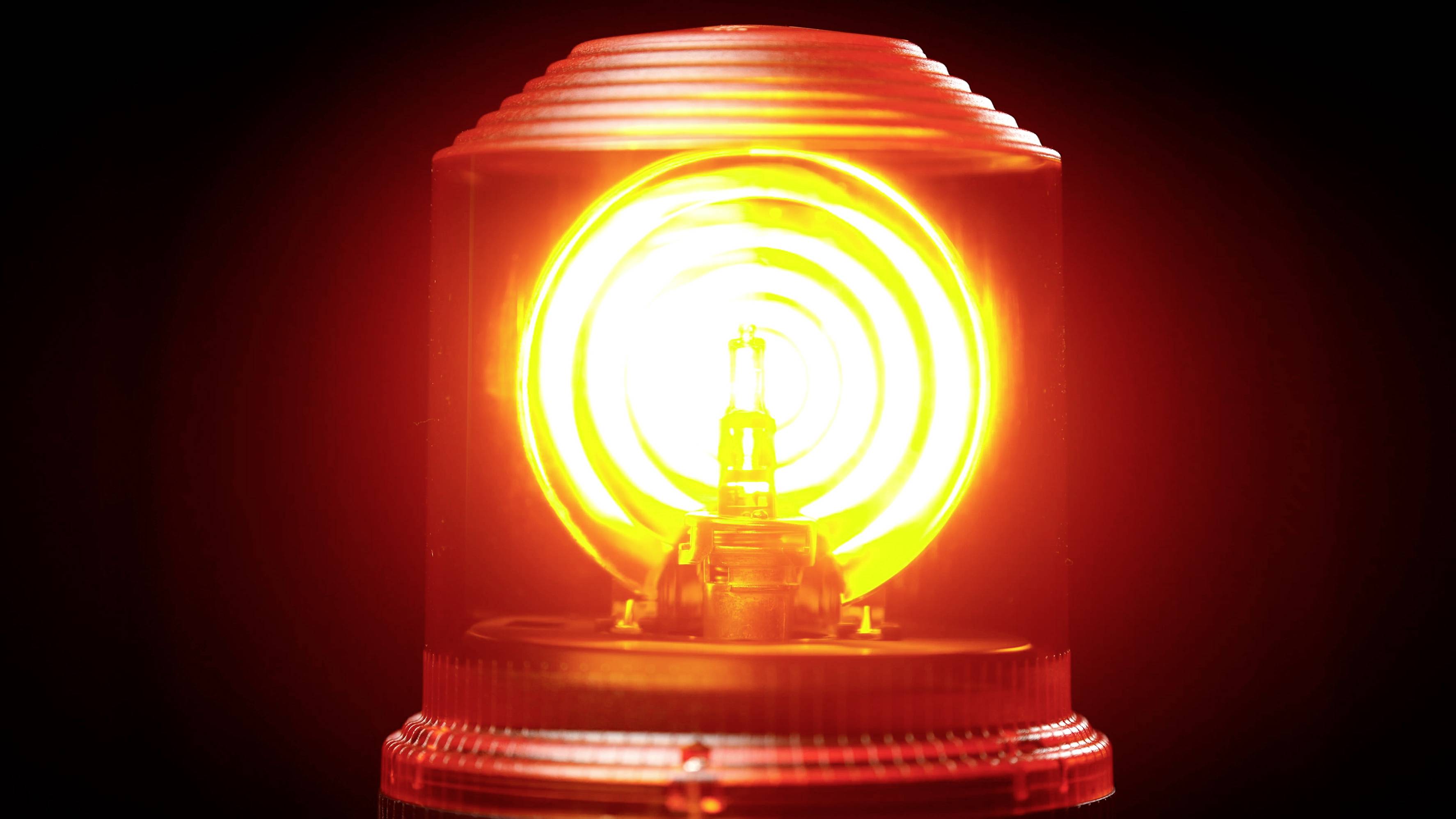 A red warning light flashes in a dark environment, signalling danger or alarm.