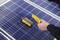 A person is holding a measuring device over a solar panel to check the performance of solar energy.