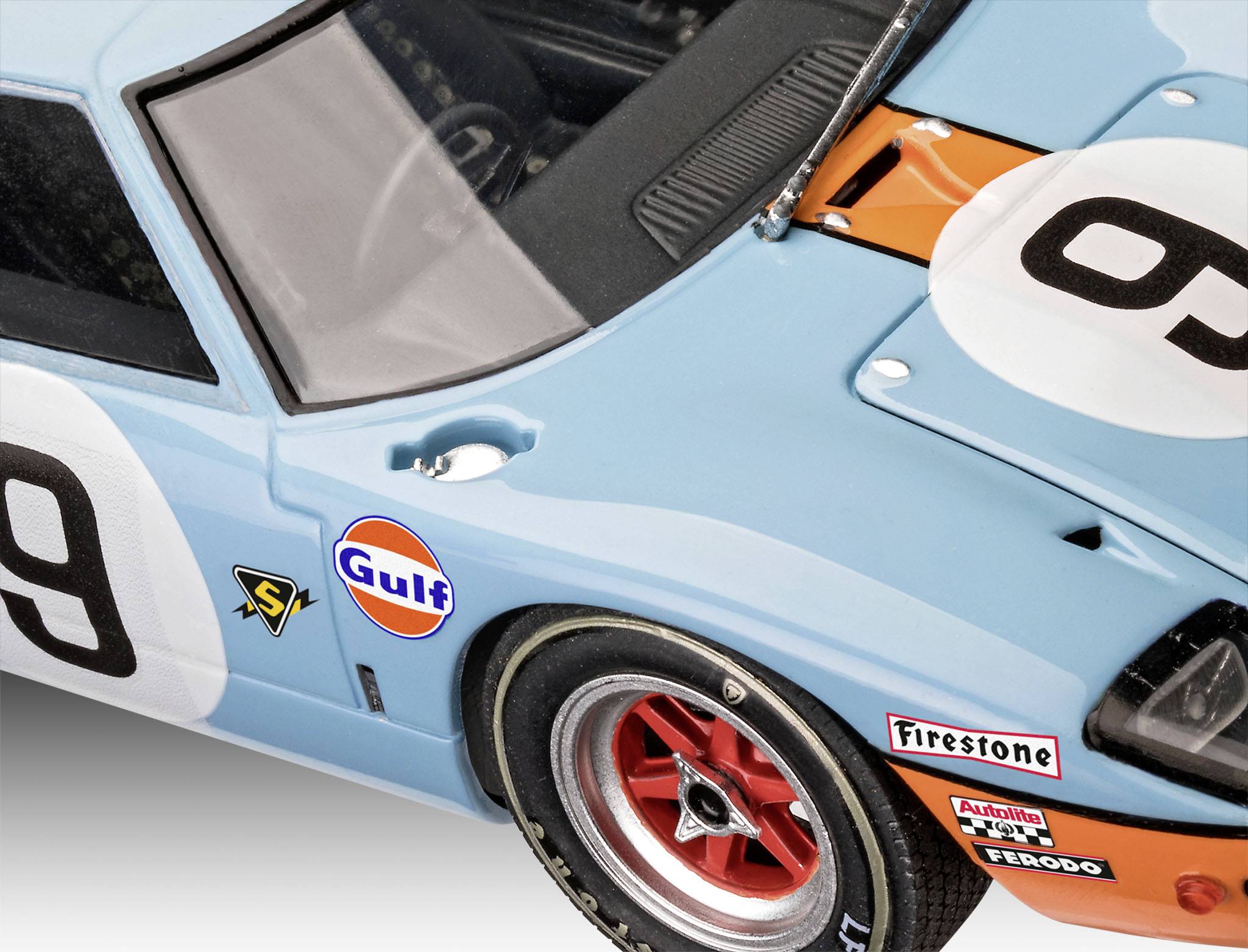 Close-up of a blue racing car with the race number 9, Gulf logo, and red wheels. The car has an iconic design from motorsport history.