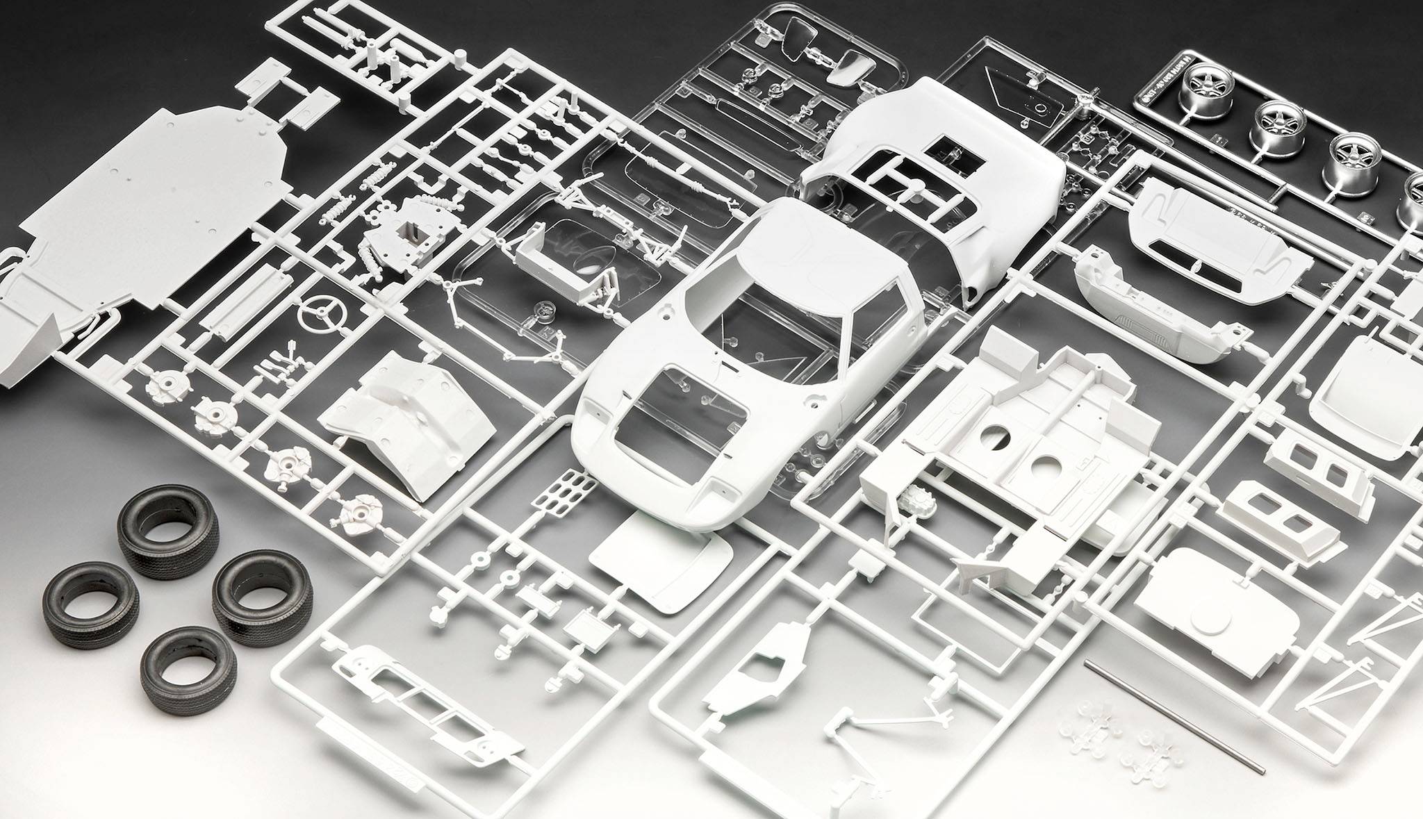 Parts of a plastic model car carefully laid out, including bodywork, wheels and tyres, ready for assembly.