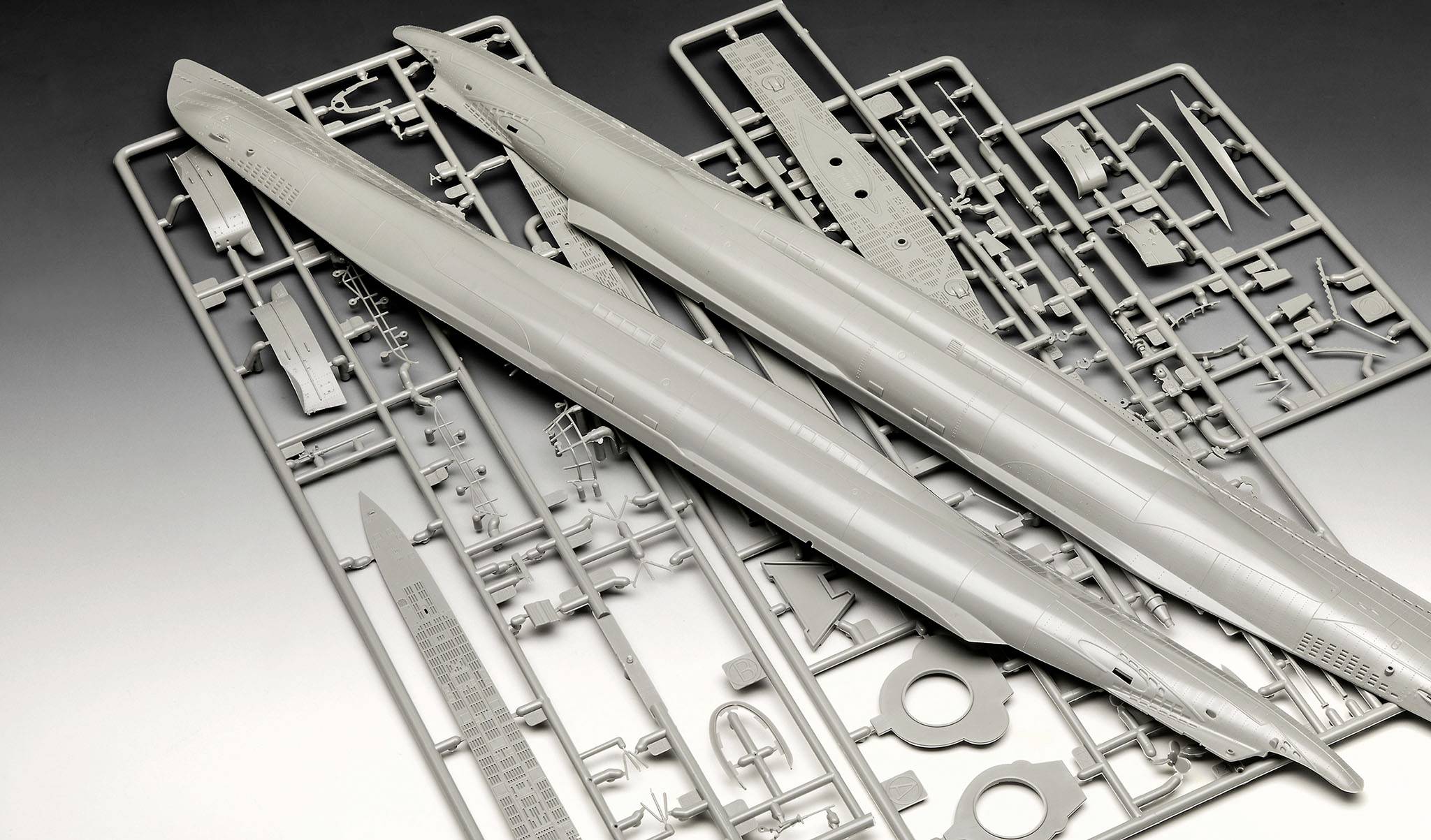 Components of a plastic model. Two hull halves of a submarine model are lying on a frame with smaller parts.