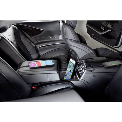 Luxurious car interior with black leather seats. Two smartphones are resting on the centre console, one charging via cable and the other charging wirelessly.