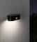 Wall light with motion sensor illuminates a grey exterior wall at dusk.