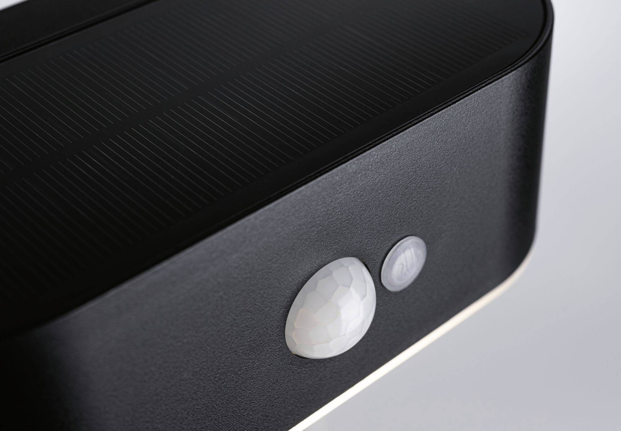 Close-up of a black device with a round, white sensor lens and an additional small sensor to the right.