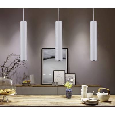 Modern dining area with three pendant lights hanging over a table decorated with crockery and a vase. Artwork on the wall in the background.